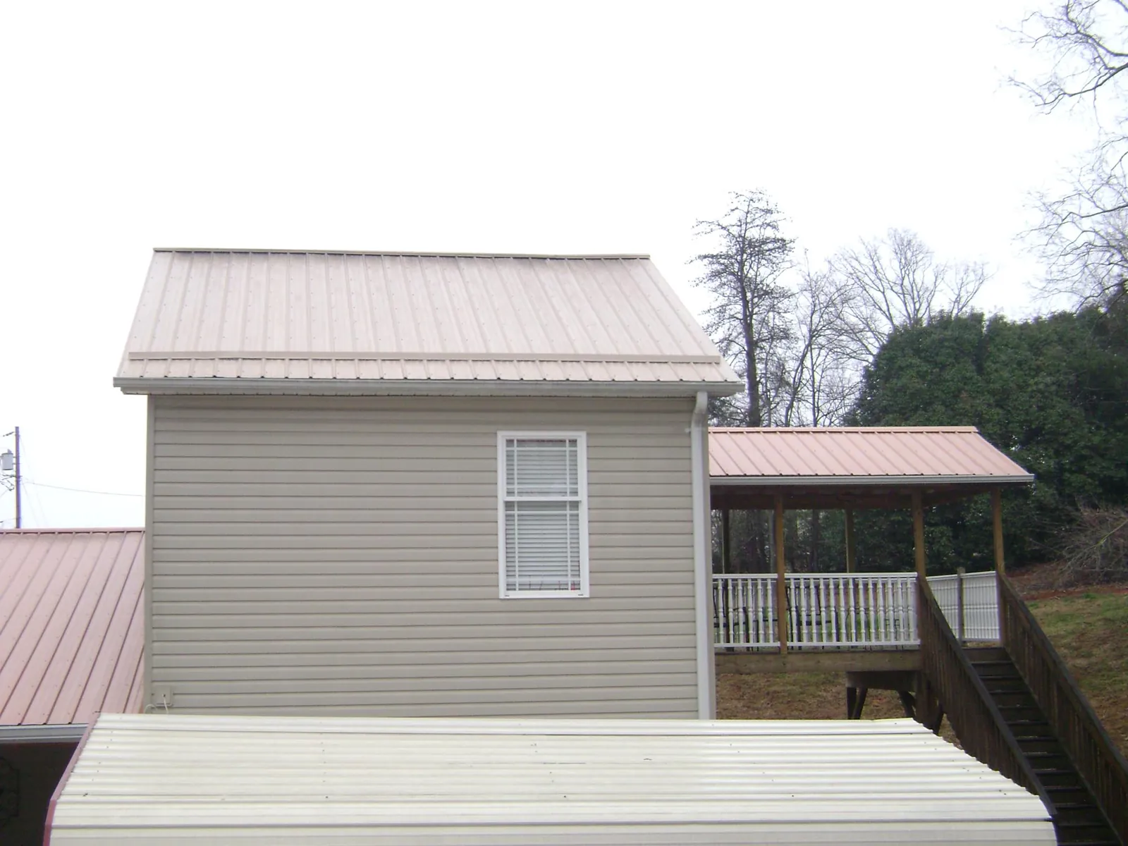 Tan metal roofs on a two story addition and attached porch, from a Roof Replacement job in Sullivan